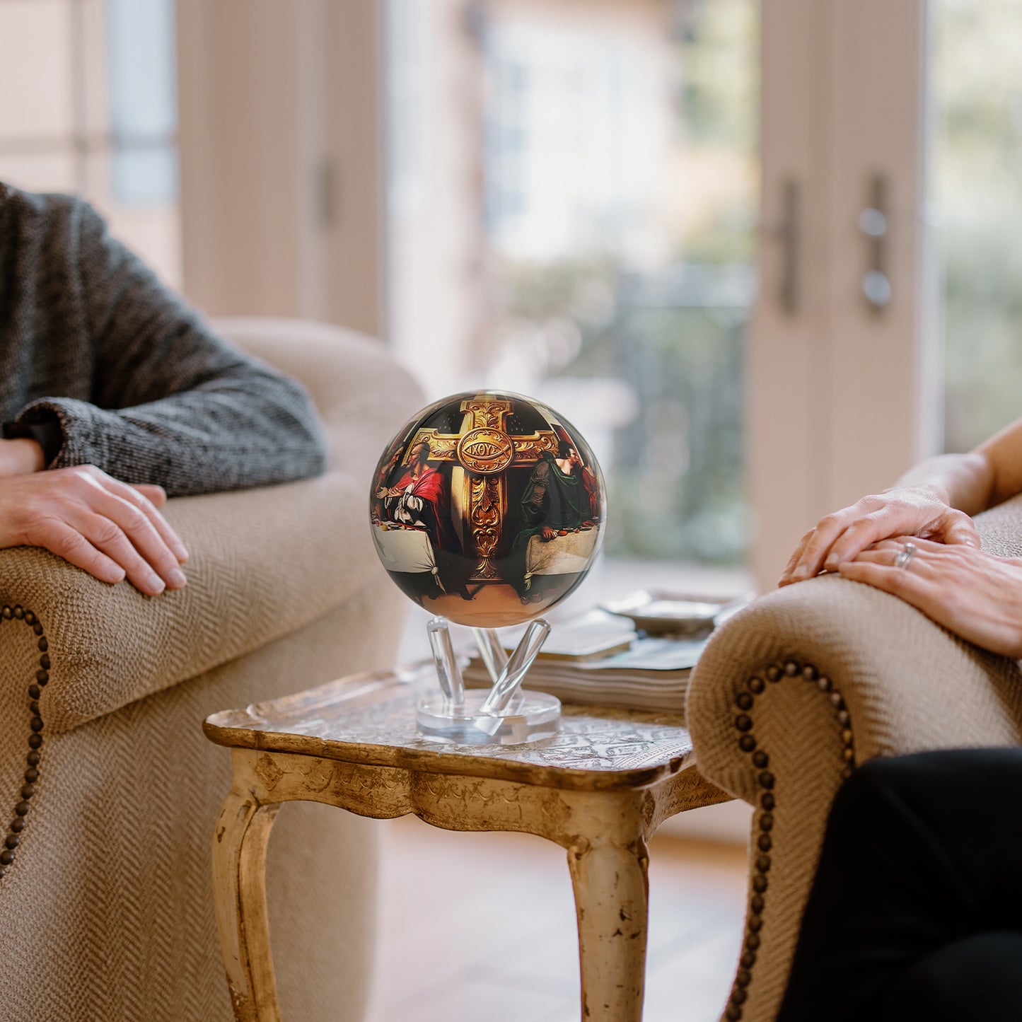 Last Supper MOVA Globe placed between two people as meaningful Christian gift and conversation piece