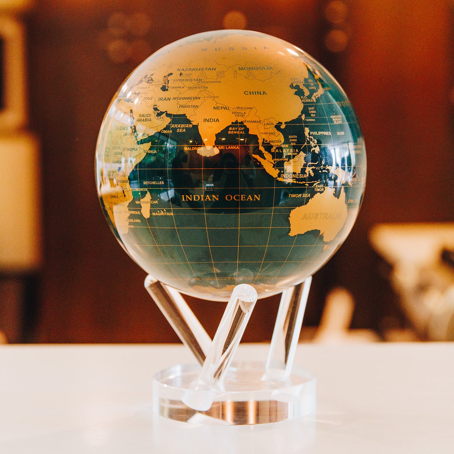 Green and Gold MOVA rotating globe on dining table, stylish home decoration and elegant conversation piece